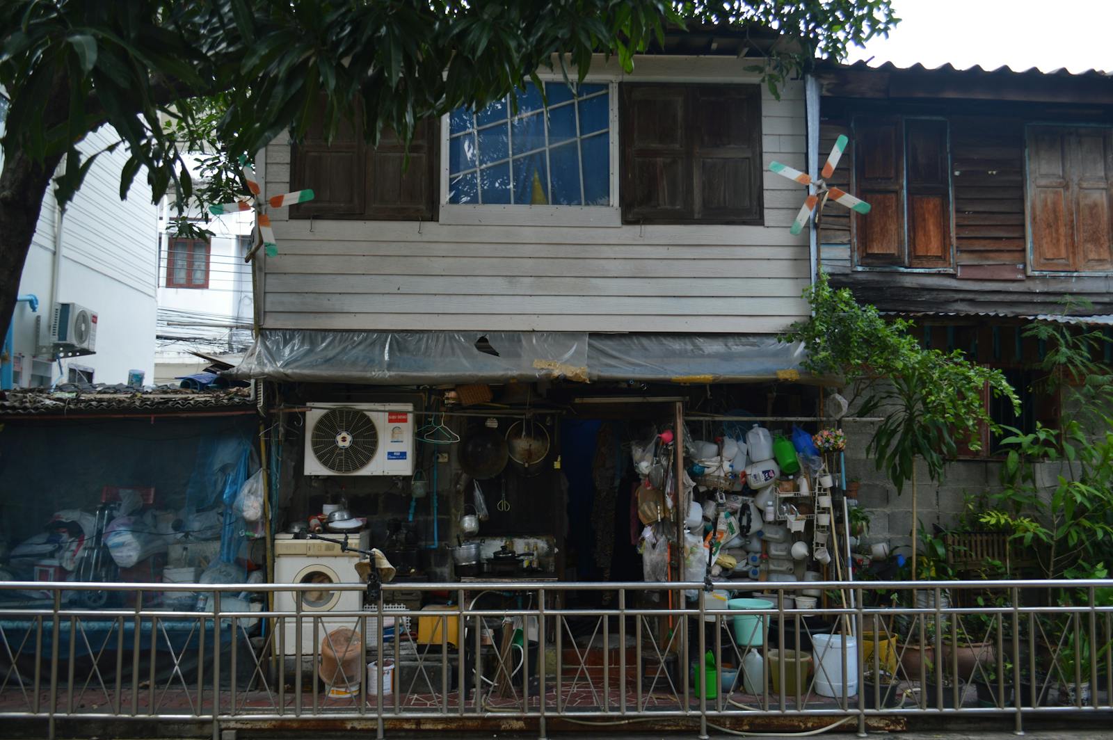 Rustic wooden house facade with various objects, fans, and greenery.
