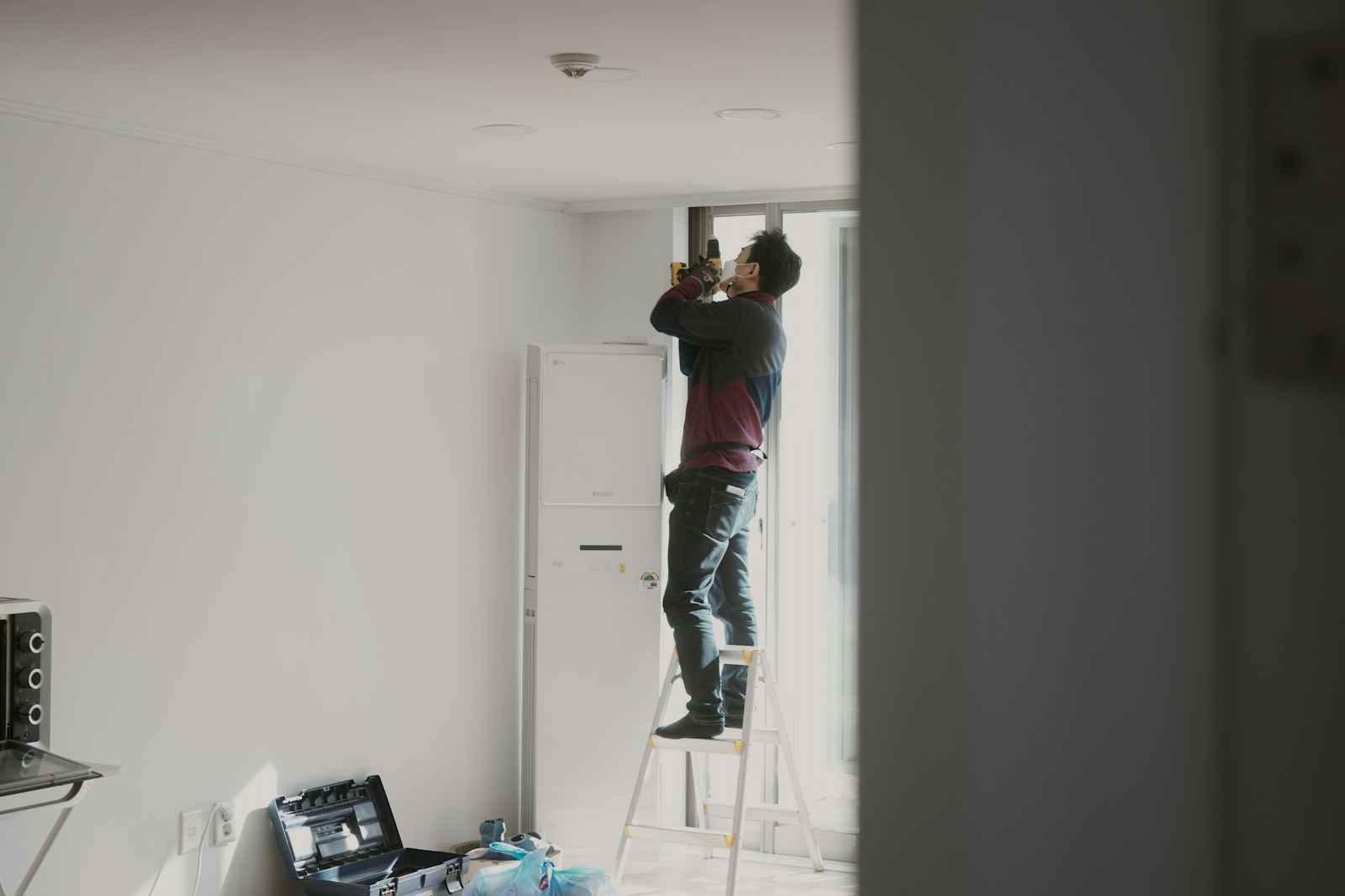 man in red shirt and blue denim jeans standing on white wooden door
