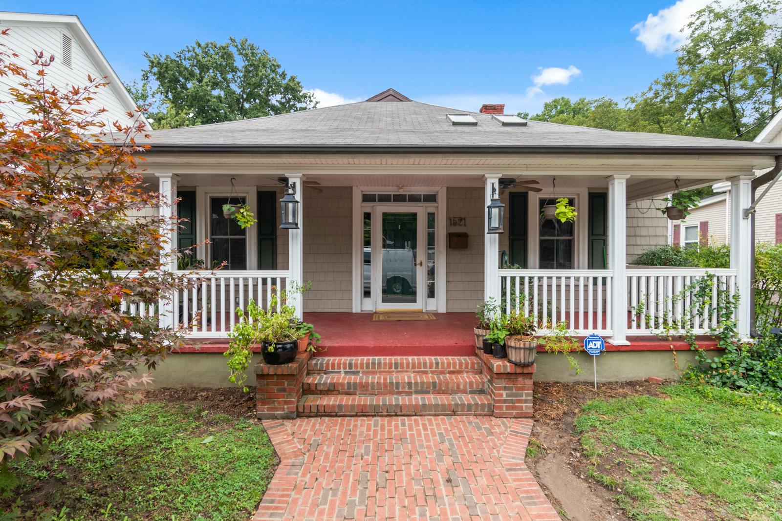Inviting suburban house with a classic porch and lush garden, perfect for real estate listings.