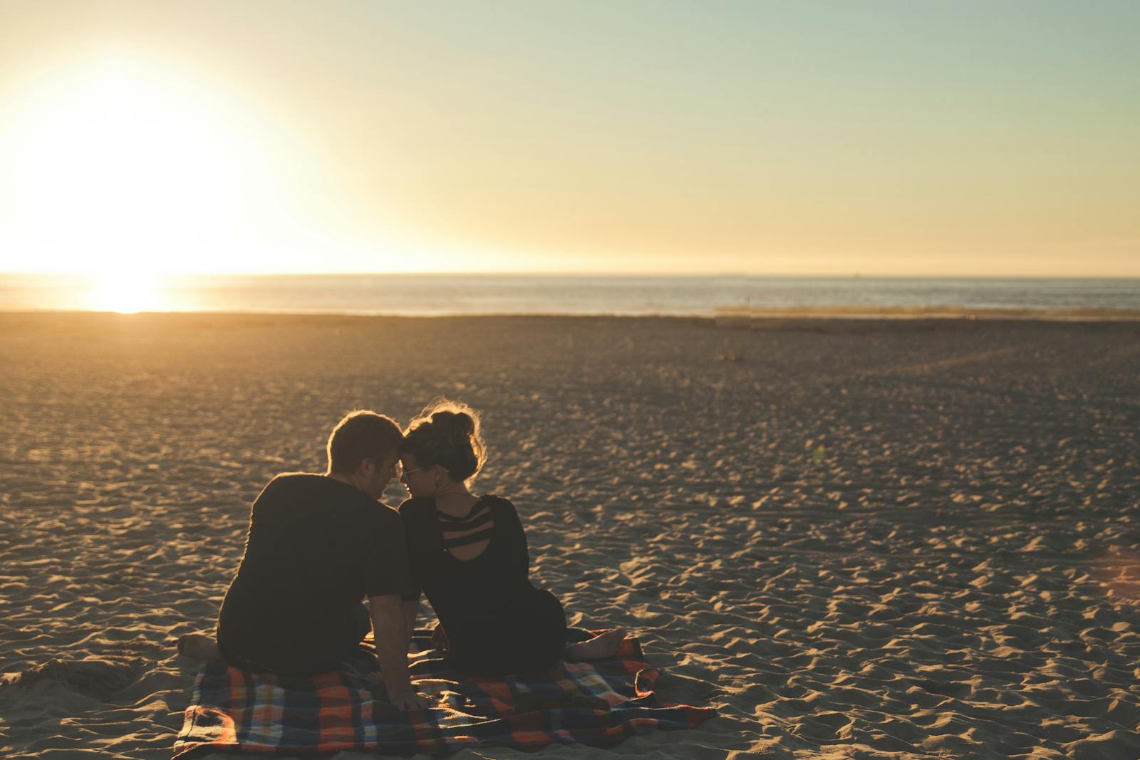 A couple enjoys sunset together on a sandy beach, capturing a moment of love and togetherness.