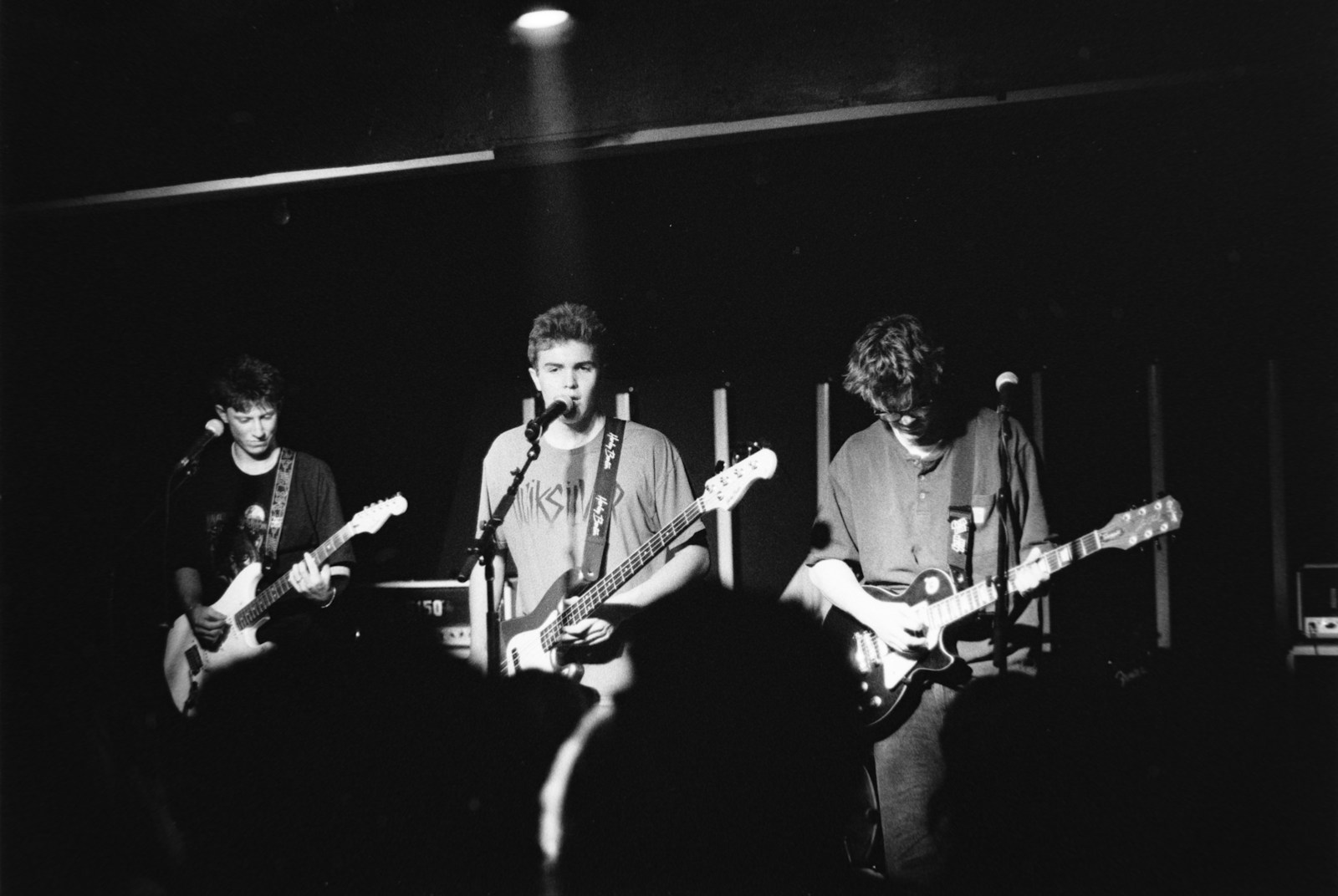 Three musicians playing guitars on a stage.