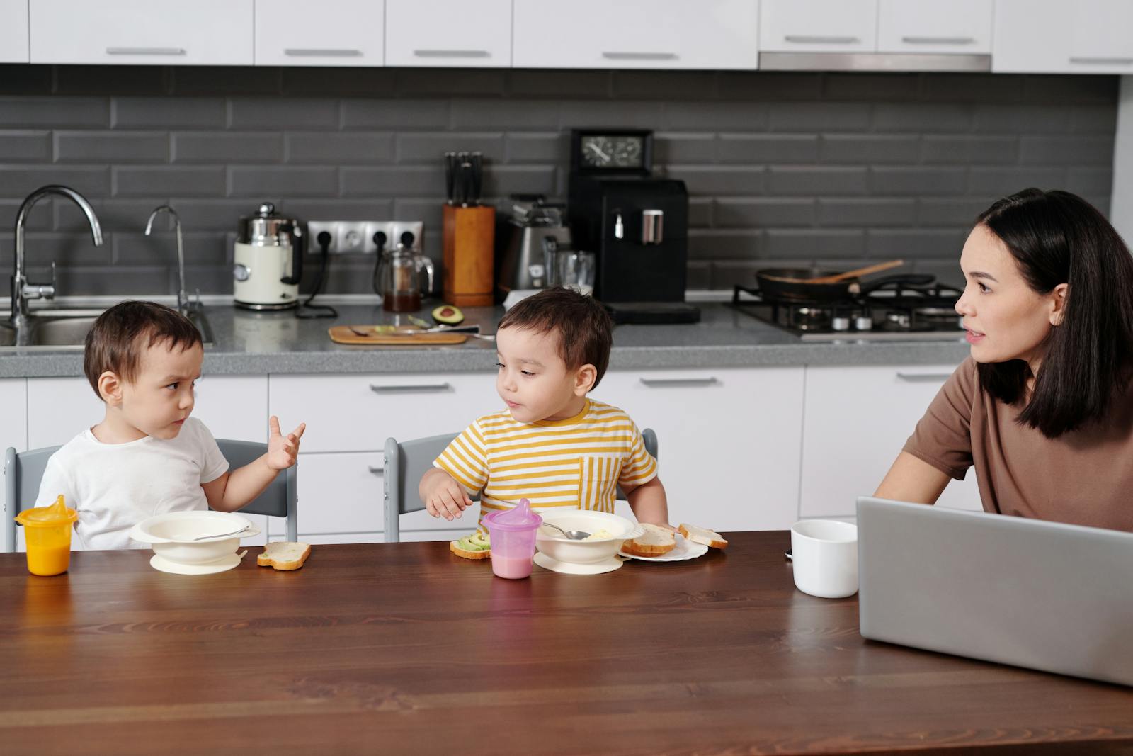 A mother and her two young boys enjoying breakfast together in a modern kitchen.