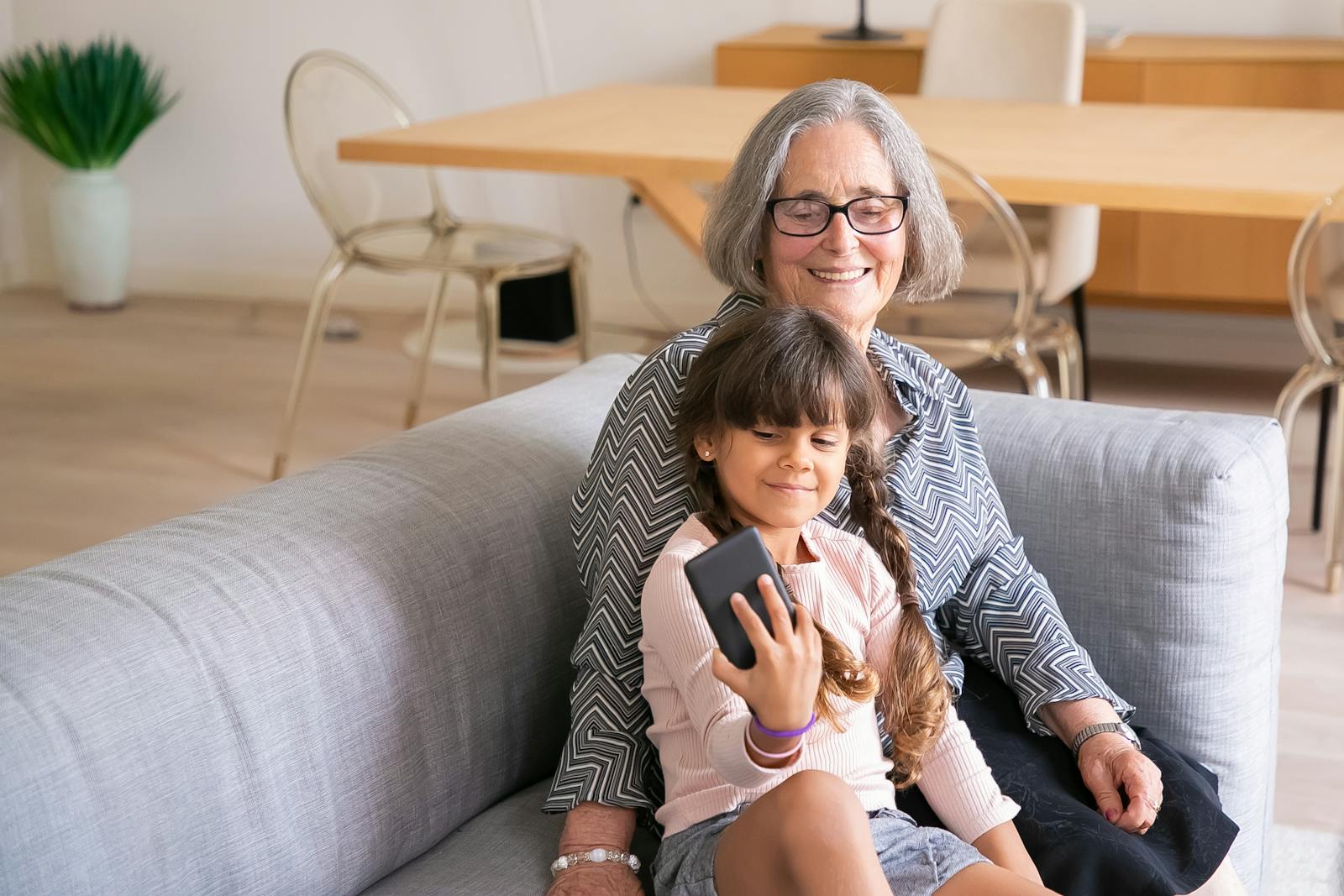 A grandmother and her grandchild share a joyful moment taking a selfie indoors.