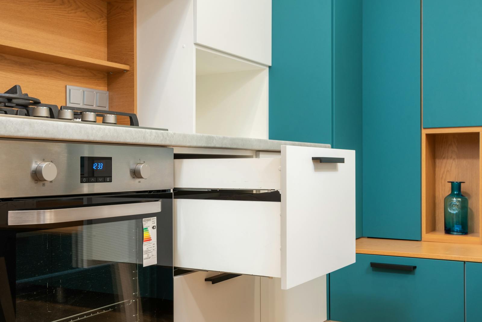 Contemporary kitchen interior showcasing a stainless steel oven and teal cabinetry.