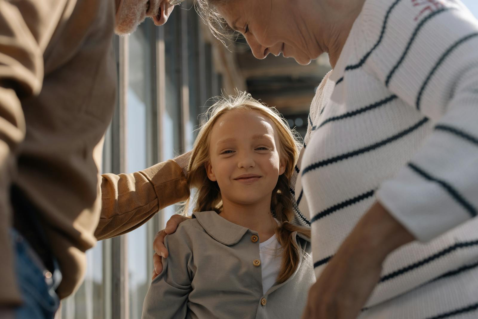 A joyful girl embraced by her loving grandparents, smiling and bonding together.