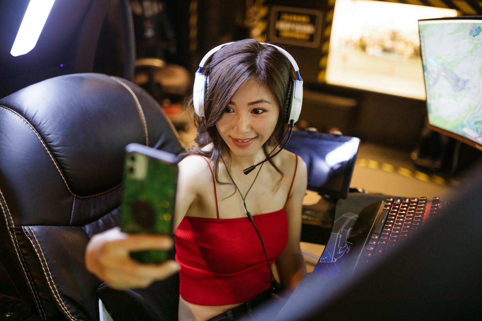 A young woman gamer with headphones taking a selfie during a gaming session.