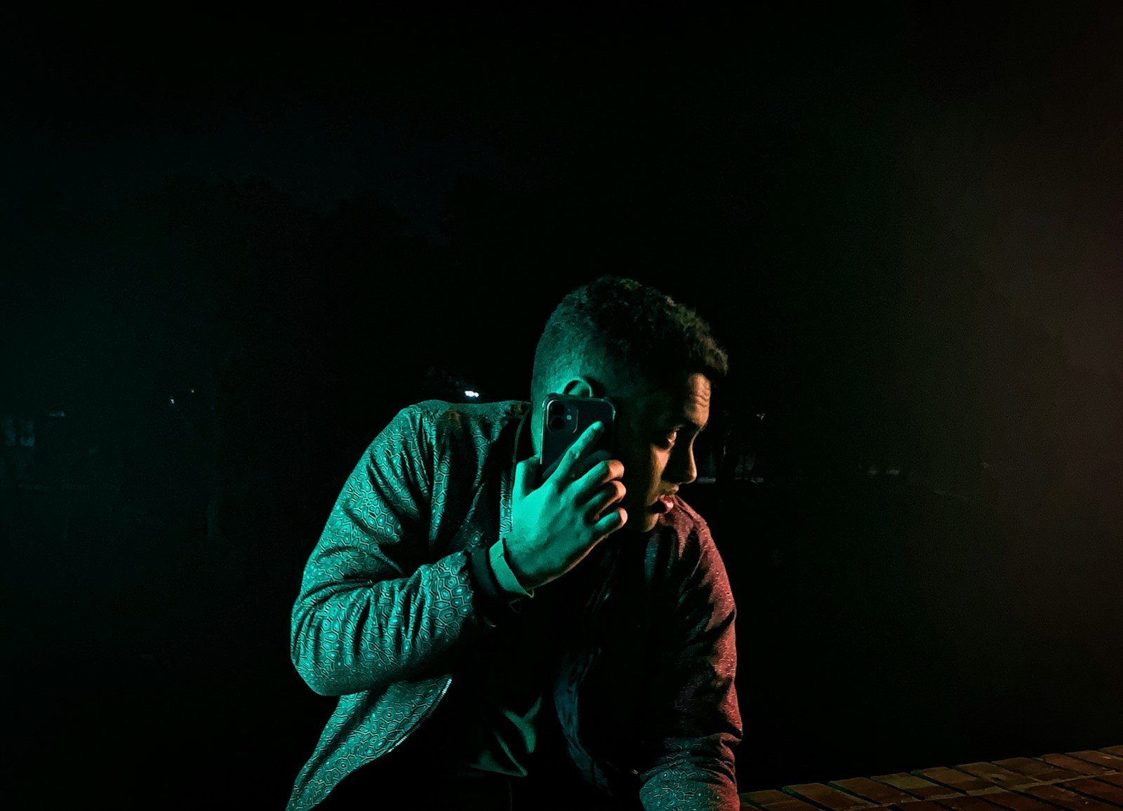 A man is holding a phone in the dark.