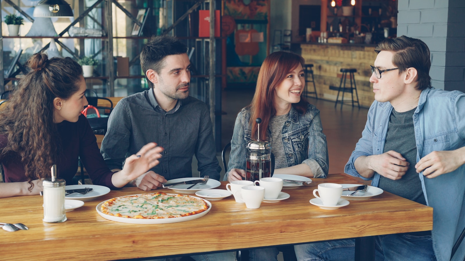 Friends are sharing pizza and conversation at a restaurant.