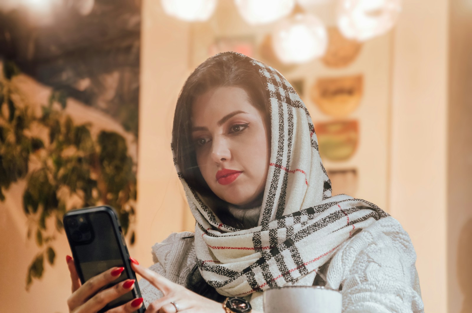 a woman in a scarf looking at a cell phone