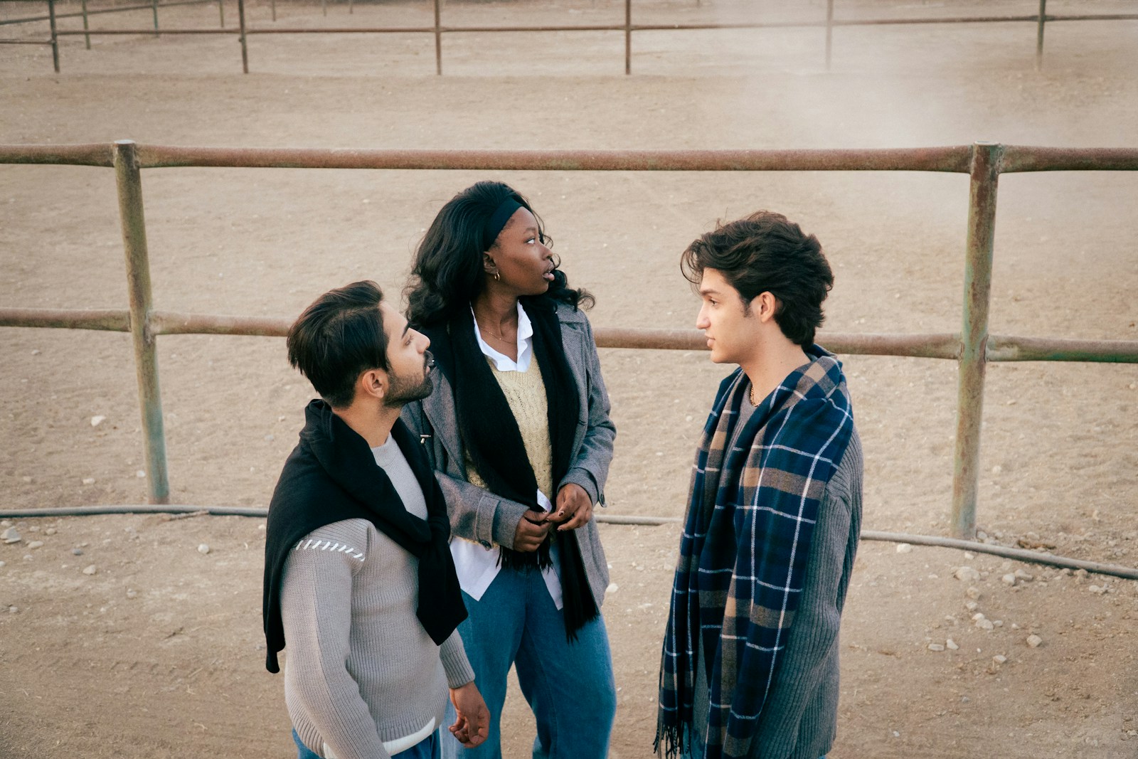 Three people talking in an outdoor enclosure.
