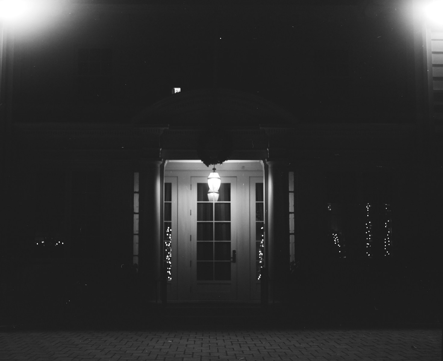 Illuminated doorway at night with brick pathway.