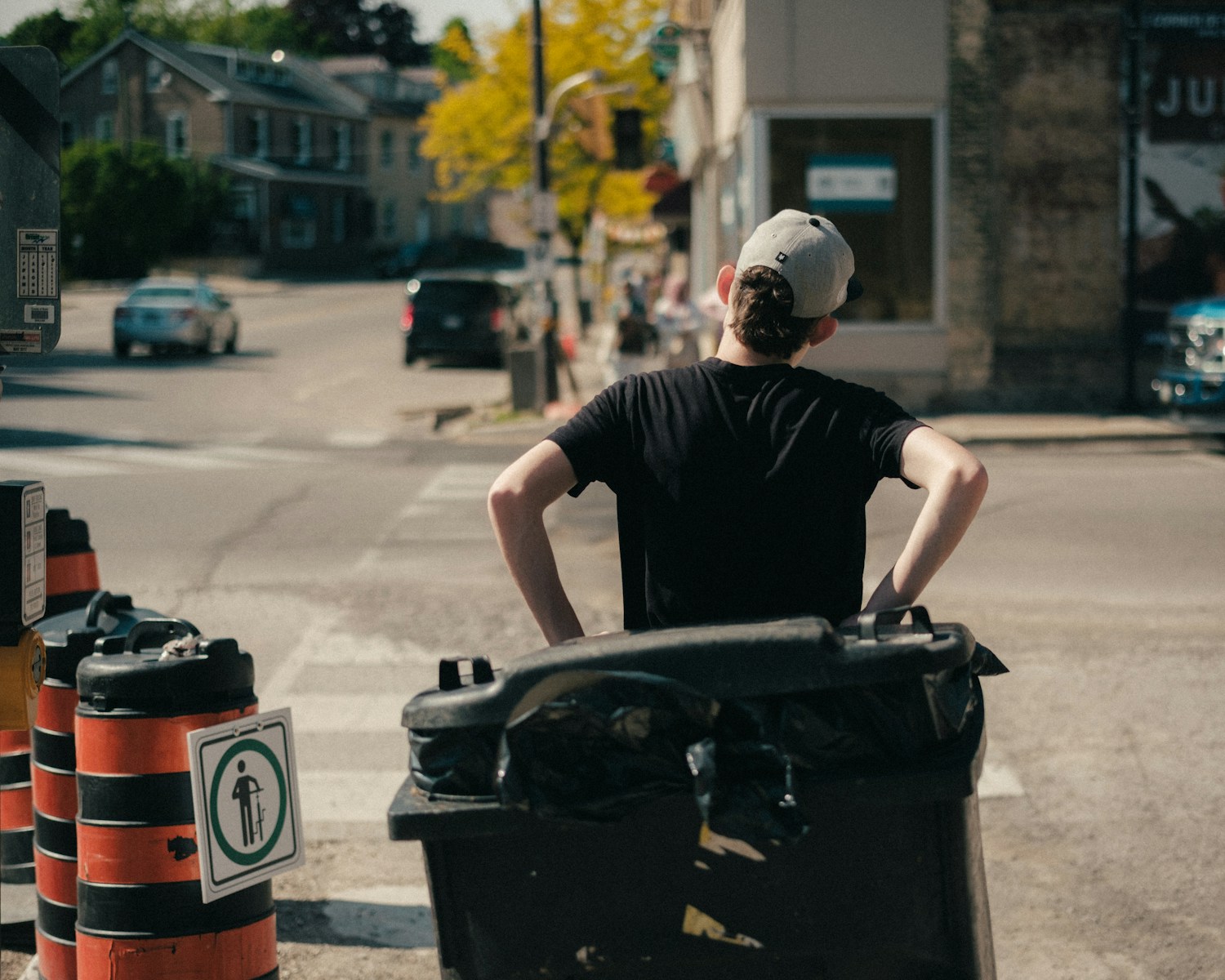 A man is standing with a trash can.