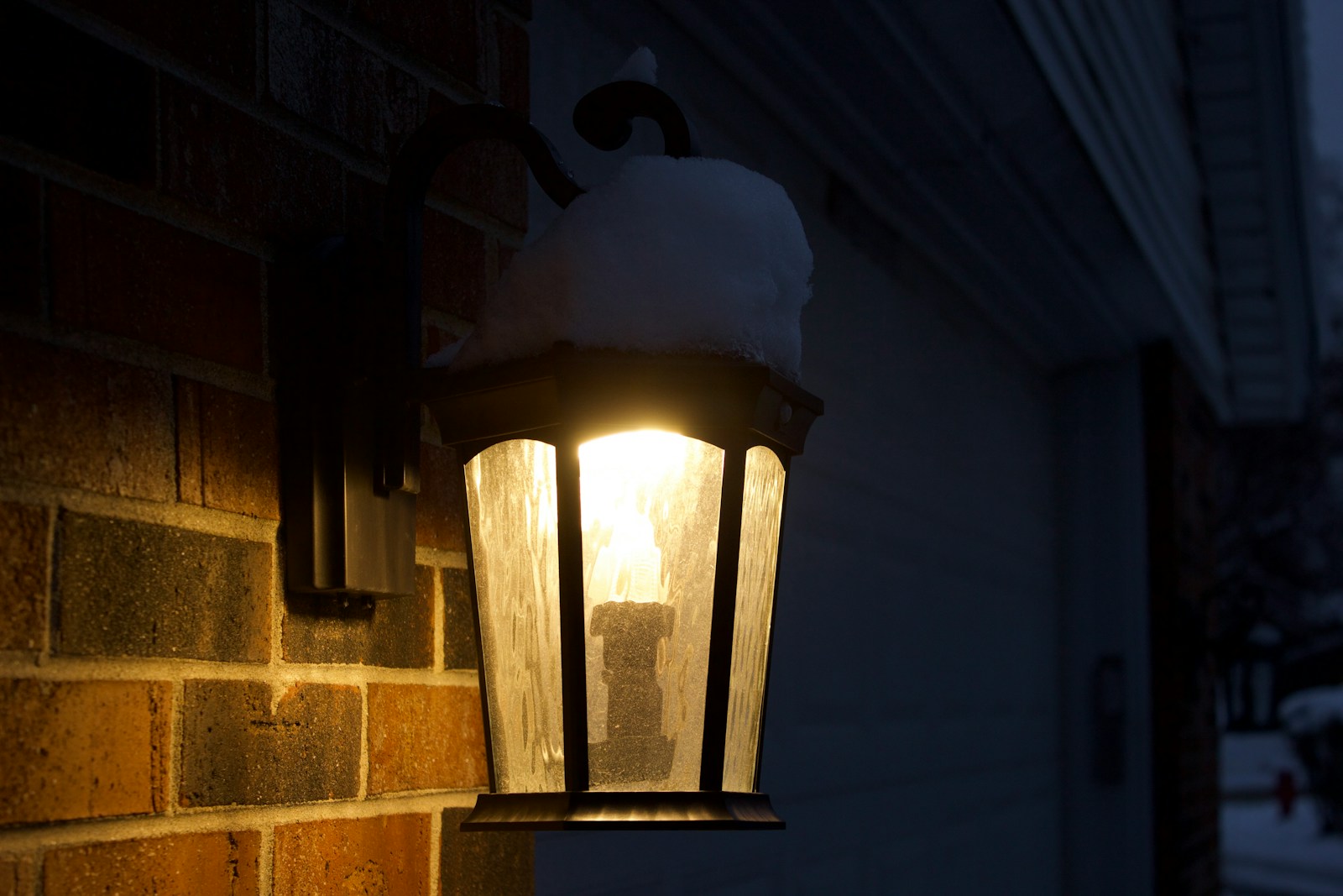 Outdoor light fixture covered in snow at night