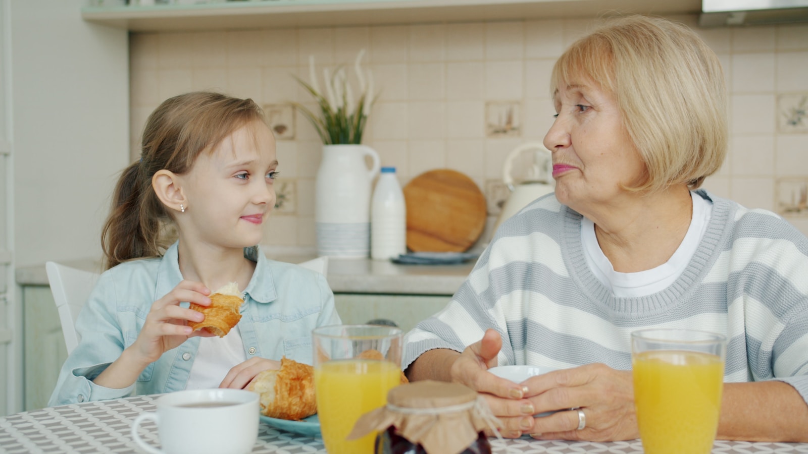 Grandmother and granddaughter sharing breakfast at table.