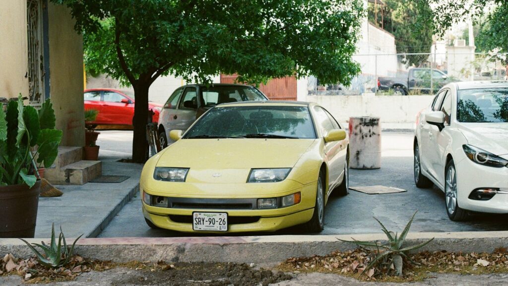 A vintage yellow car parked among other vehicles in a residential area.