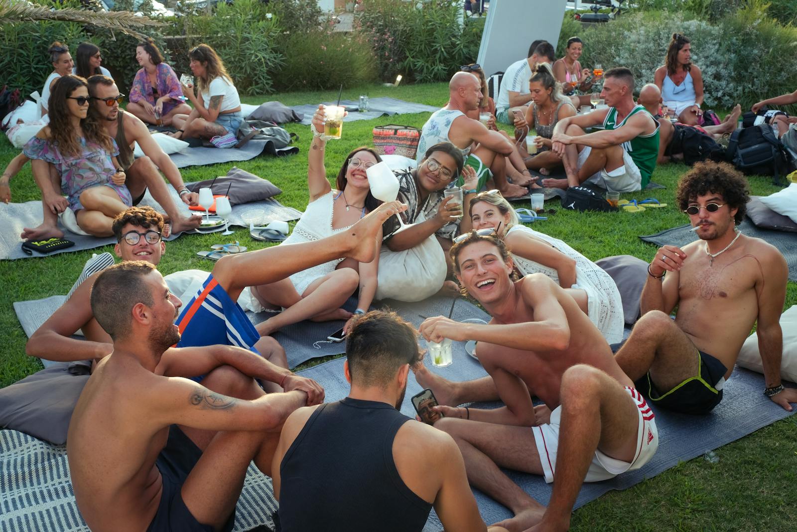 Group enjoying an outdoor summer party in Cervia, Italy, with laughter and drinks.