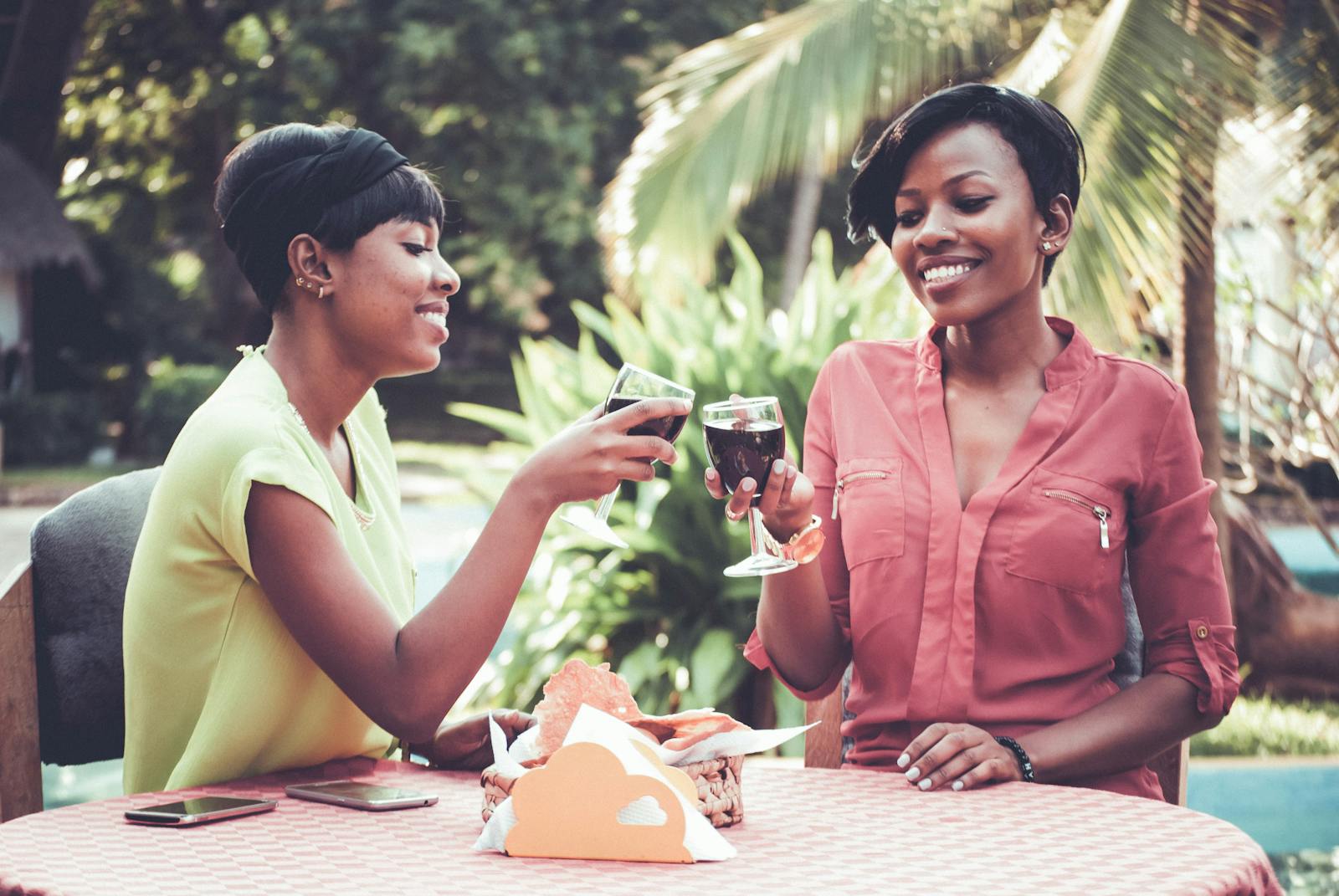 Two women happily sharing wine outdoors. A moment of relaxation and enjoyment.