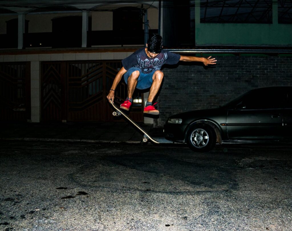 A skateboarding man performs an ollie at night on a city street, showcasing dynamic action.