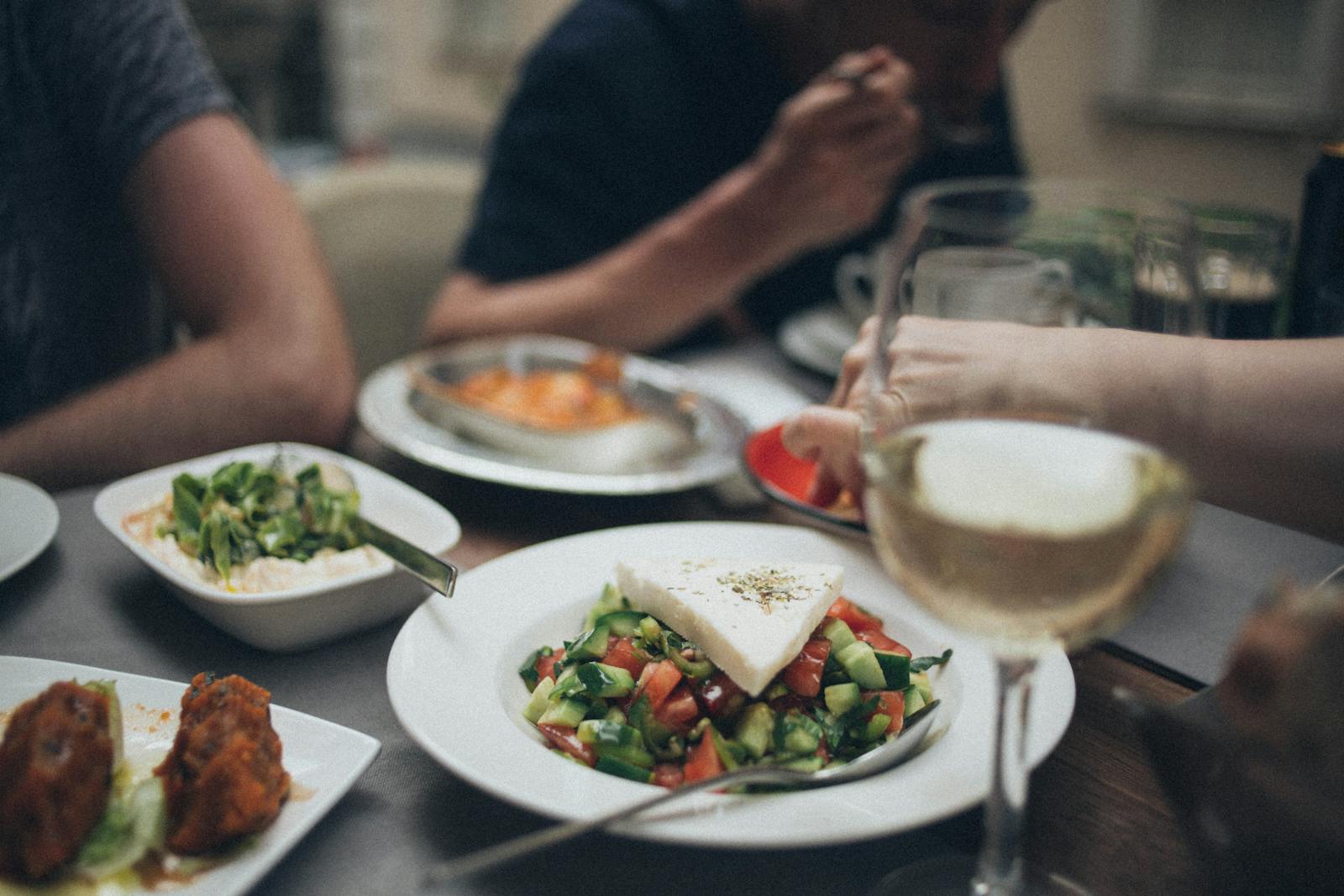 A beautifully arranged dinner setting featuring fresh salad and white wine, perfect for a fine dining experience.