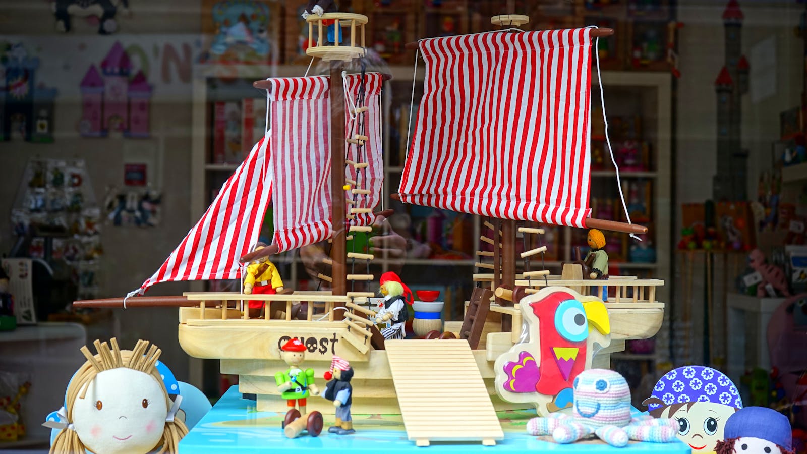 Vibrant toy shop window featuring a wooden ship and colorful stuffed animals.