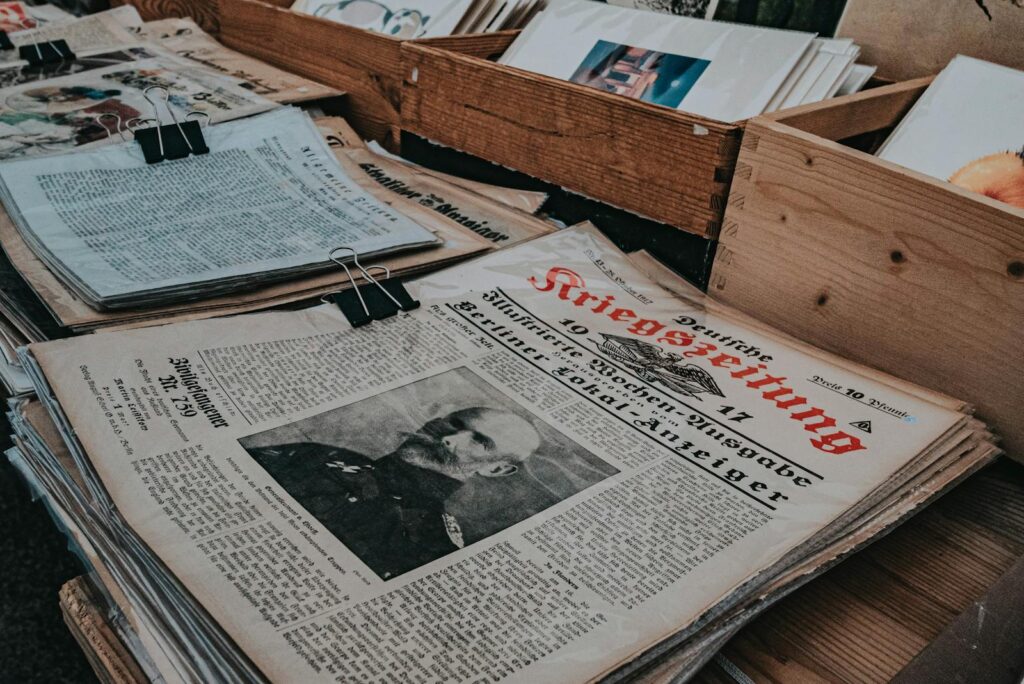 Retro German newspapers featuring historical portraits in wooden boxes, evoking a vintage aesthetic.