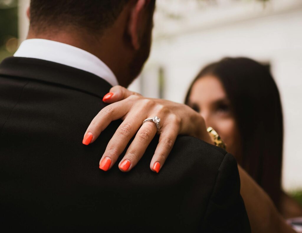 Close-up of a couple's engagement with a diamond ring highlighted on manicured nails.