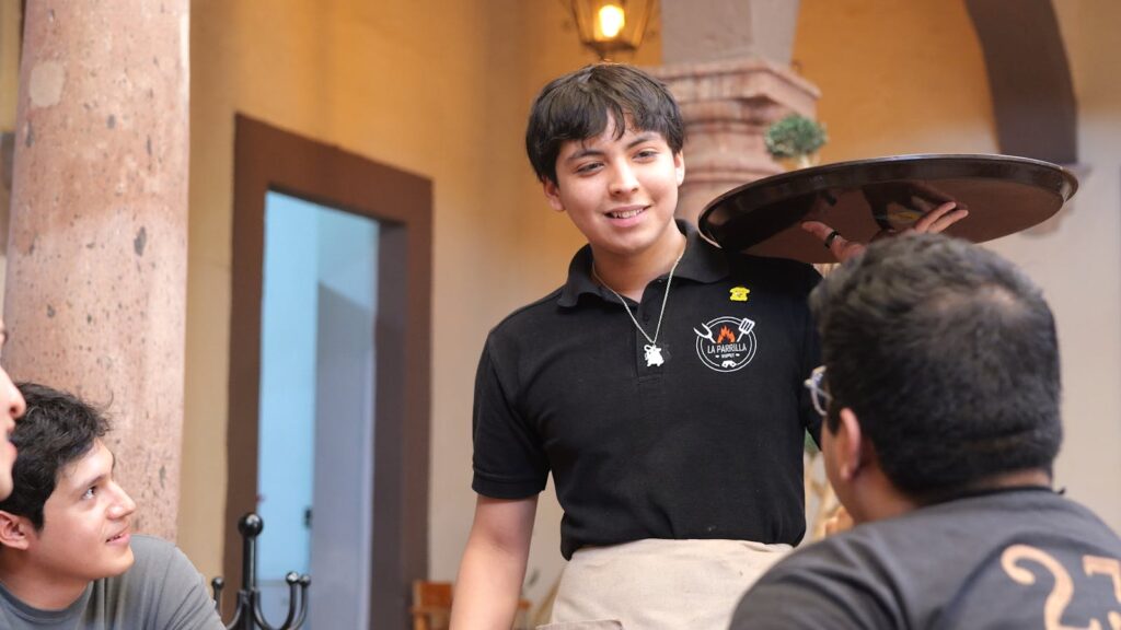 A cheerful waiter interacting with customers at a restaurant in Guanajuato, Mexico.