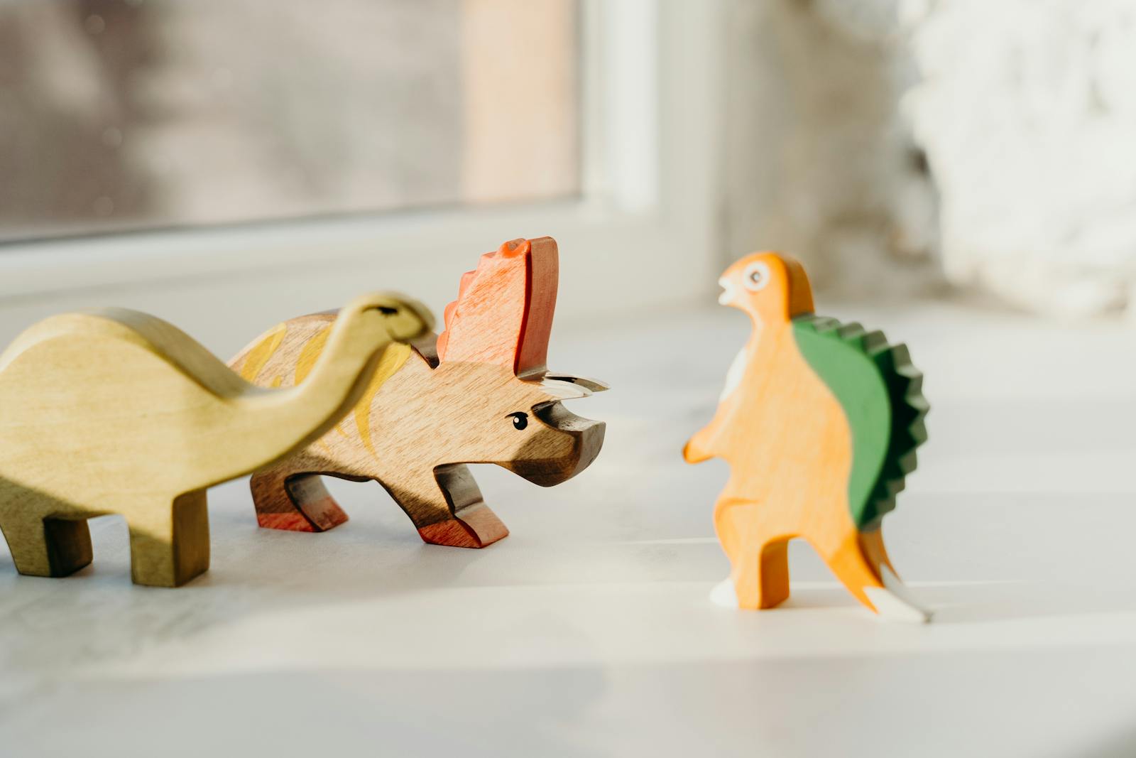 Engaging wooden dinosaur toys on a sunlit surface, perfect for children’s imagination.