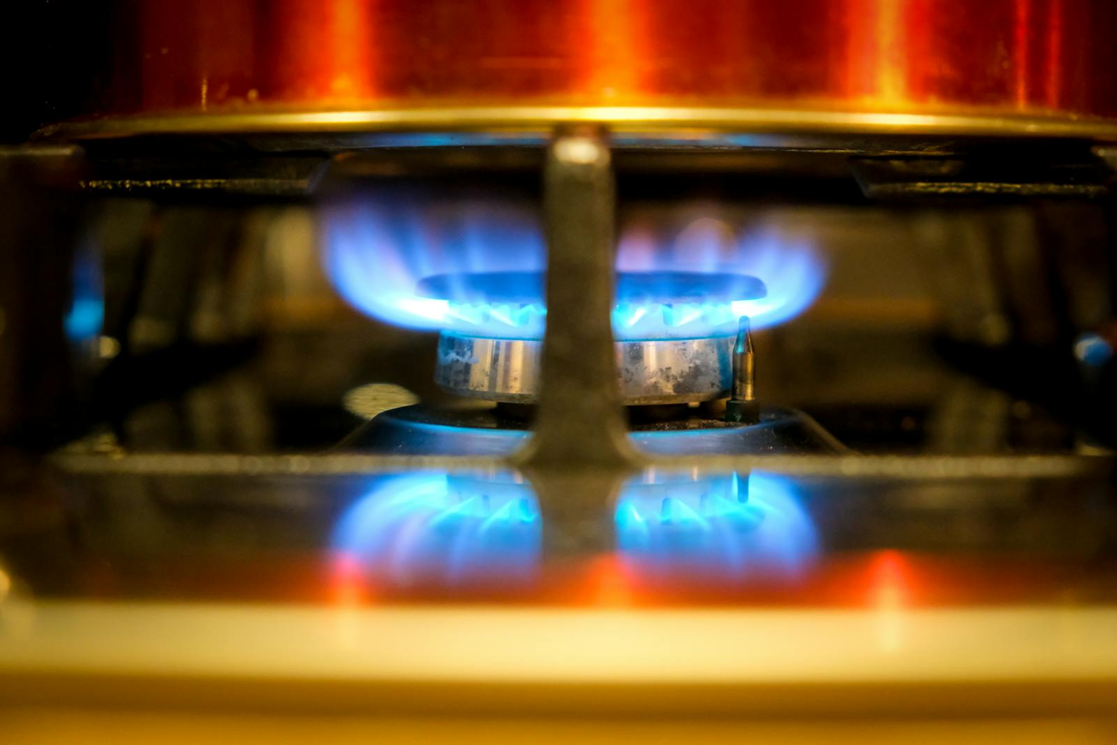 Close-up of a blue flame on a gas stove burner, showcasing kitchen heat and cooking.