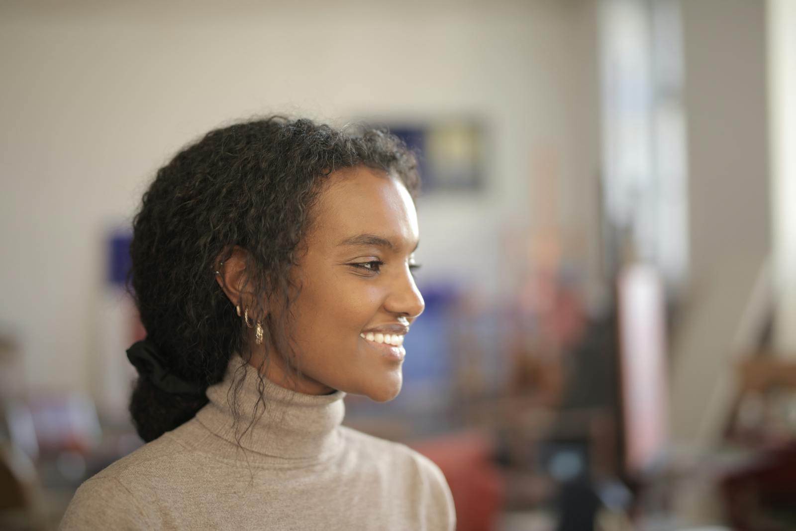 Profile of a smiling woman indoors, exuding warmth and positivity in natural light.