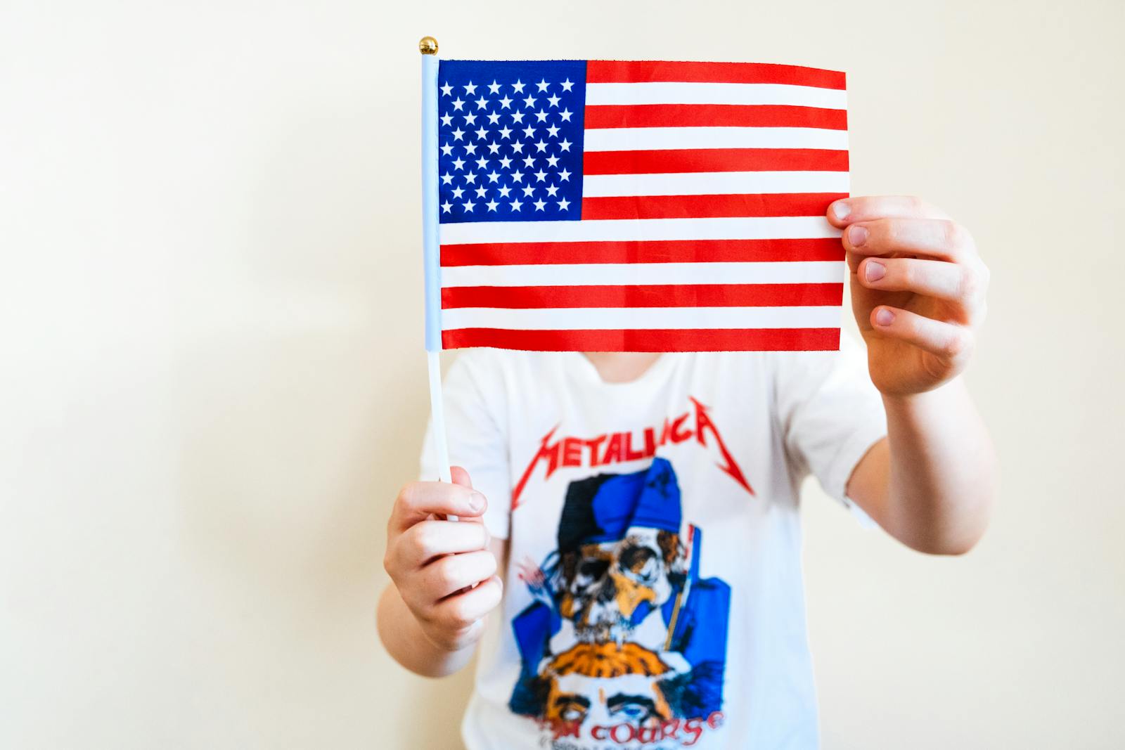 A person holds an American flag while wearing a Metallica t-shirt, symbolizing patriotism and music.
