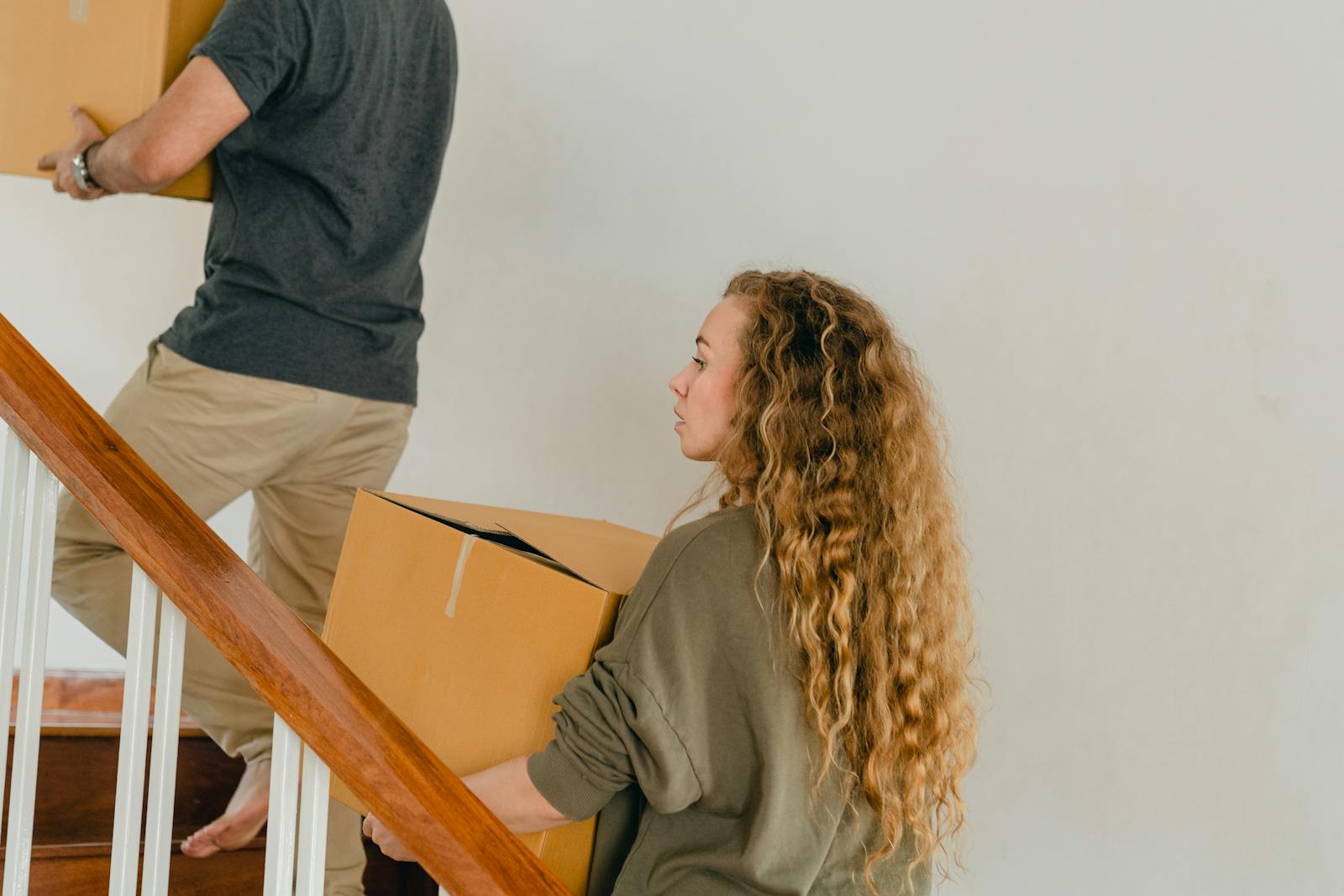 Young couple carrying boxes upstairs during a house move, illustrating relocation and new beginnings.