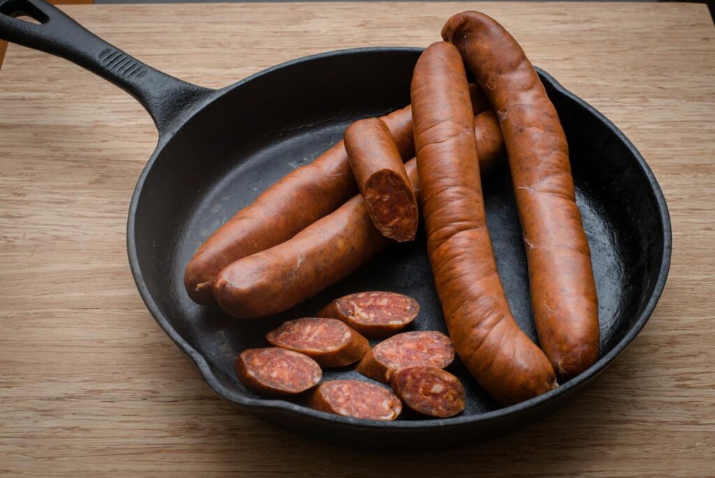 Delicious smoked sausages in a cast iron pan. Perfect for gourmet cooking.