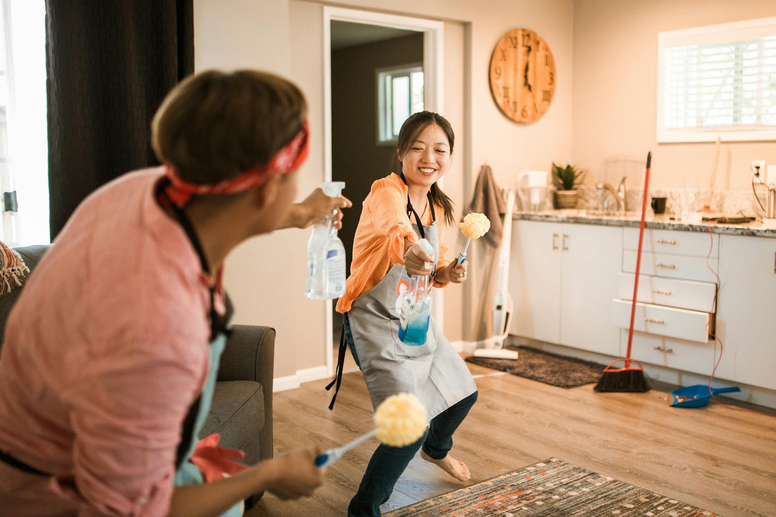 Asian couple having fun while cleaning their home, enhancing a cheerful atmosphere.