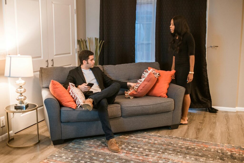 An interracial couple having a conversation in a modern living room setting, showcasing domestic life.