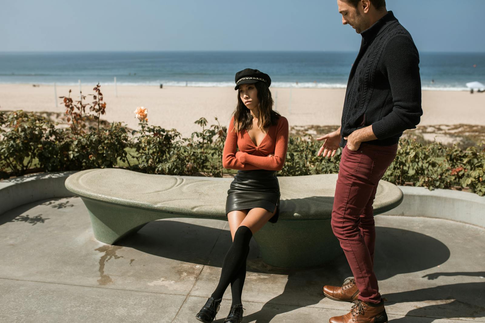 A multiracial couple having a disagreement by the beach on a sunny day.