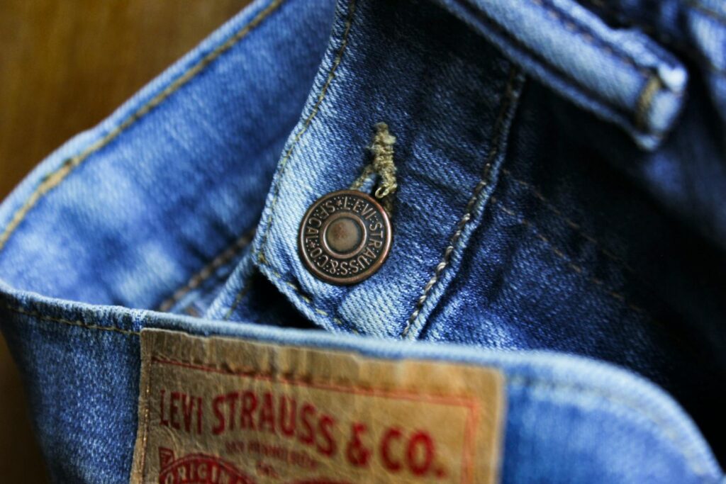 Detailed close-up photo showcasing the button and label on denim jeans, emphasizing Levi Strauss branding.