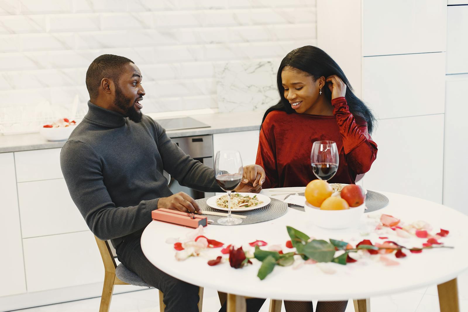 Couple enjoying a romantic dinner at home with wine and flowers.