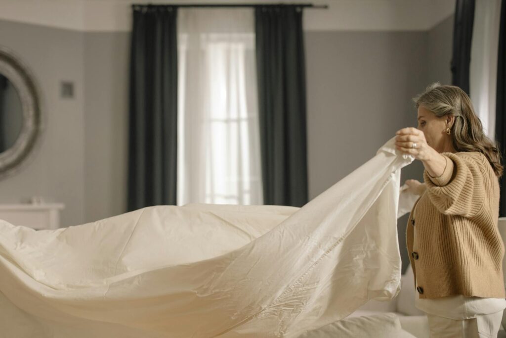 Elderly woman making a bed indoors, showcasing a serene and tidy home environment.