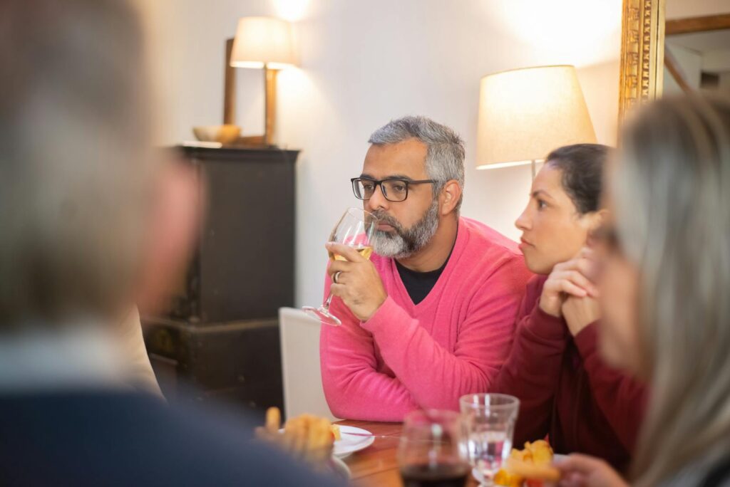 A group of friends shares wine and conversation during a cozy dinner indoors in Portugal.