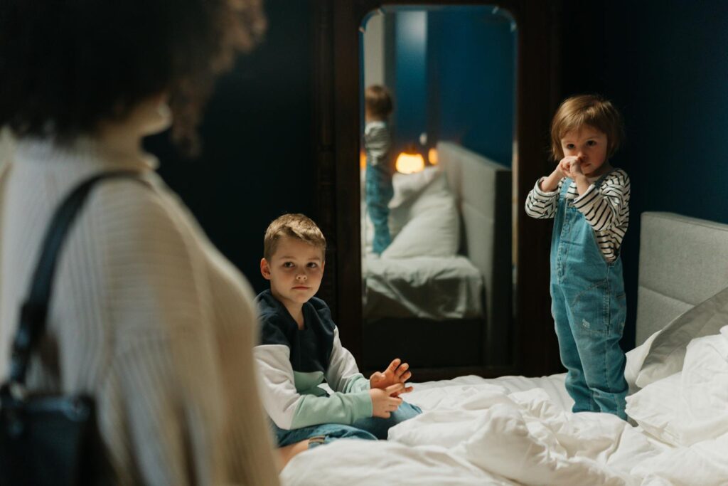 Woman and kids in a bedroom with a mirror, capturing a serene family moment.