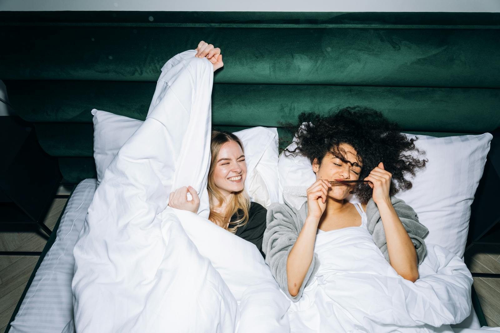 Two young women enjoying a fun sleepover, sharing smiles and laughter in a cozy bedroom.