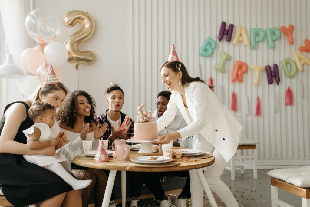 A joyful family celebrating a birthday party indoors with cake and balloons.
