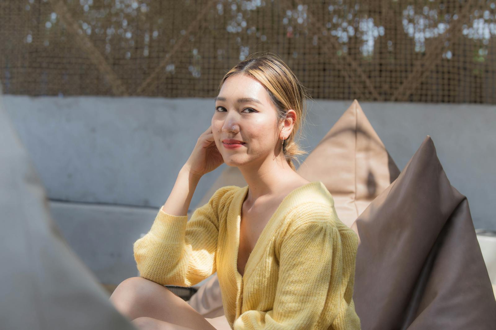 Cheerful woman wearing a yellow cardigan, sitting outdoors, enjoying a sunny day.