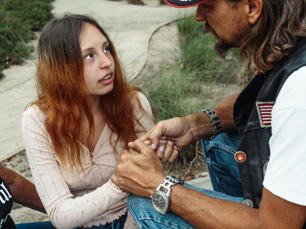 A father and daughter share a close moment outdoors, emphasizing support and bonding.