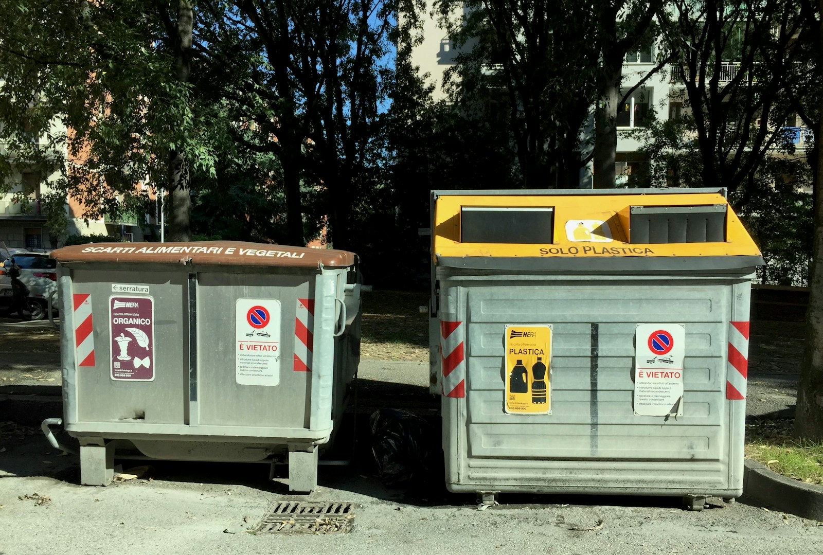 Two recycling bins are sitting outdoors.