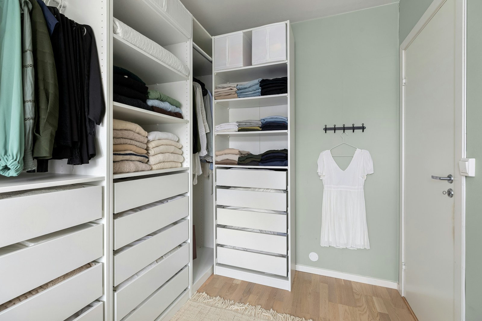 A walk in closet filled with lots of white drawers