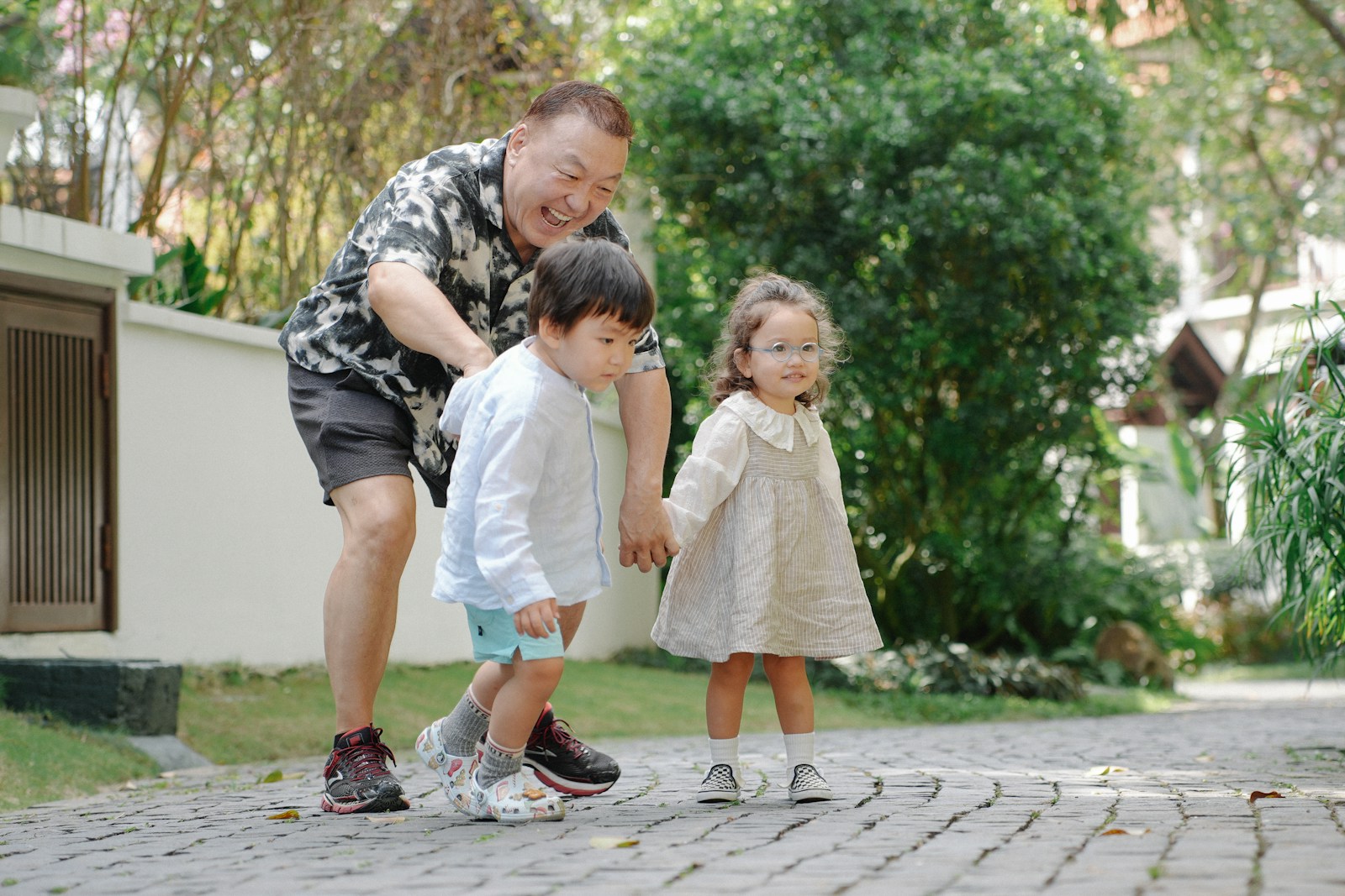 Man with two children walking on a paved path.