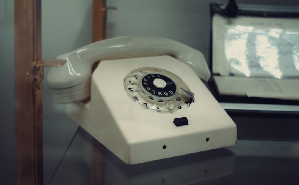 A vintage rotary dial telephone on a desk.