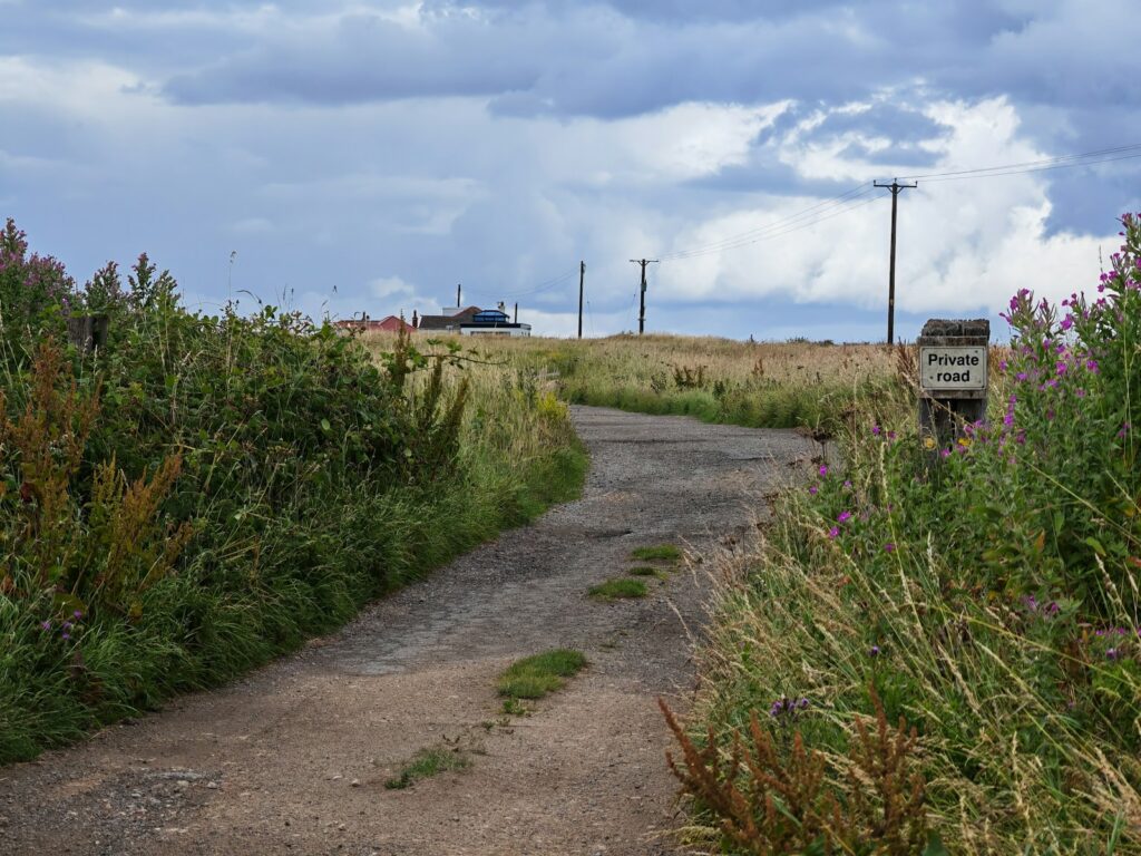 a dirt road with a sign on the side of it